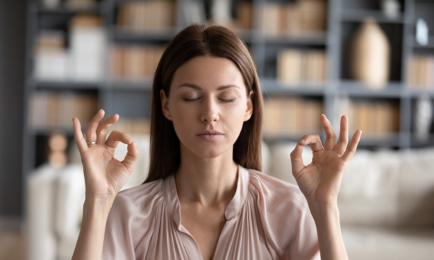 Photo présentant une femme d'environ trente ans qui médite les mains en position du lotus.