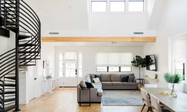 Photo intérieur d'une maison contemporaine. Il s'agi d'une pièce de vie, les murs sont blanc, au sol il y a du parquet couleur bois, un canapé meuble al pièce.