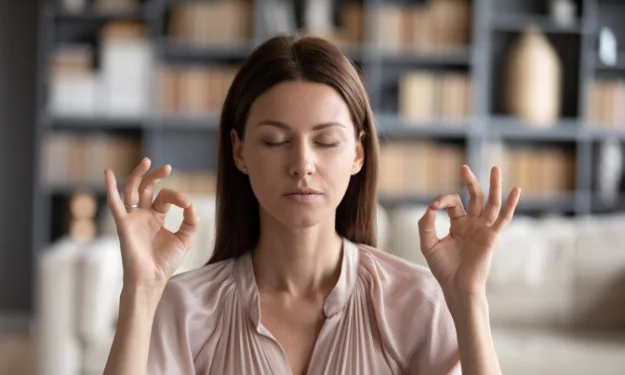Photo présentant une femme d'environ trente ans qui médite les mains en position du lotus.